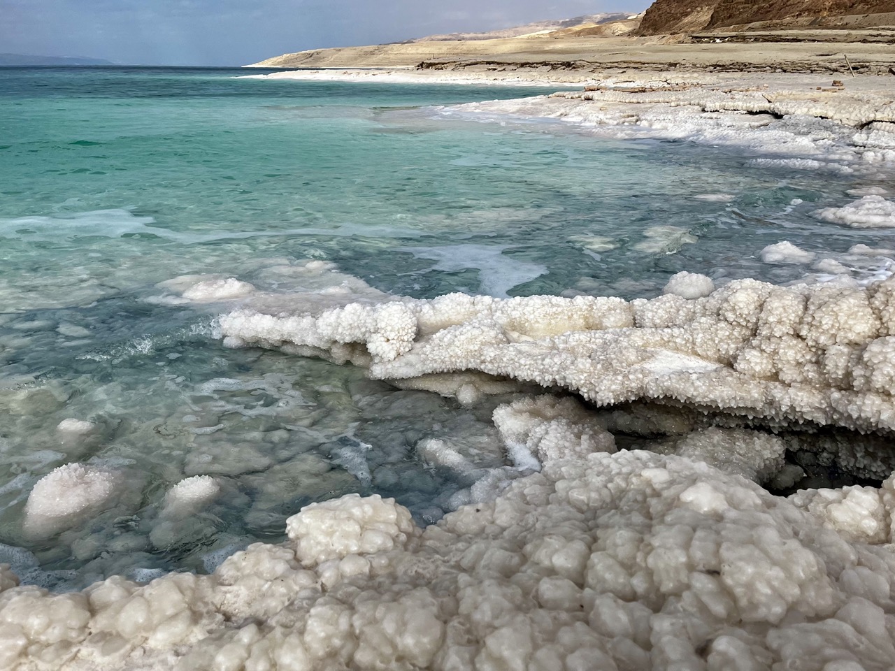 Salt crystals crusting the shoreline, and the impossibly blue water of the Dead Sea