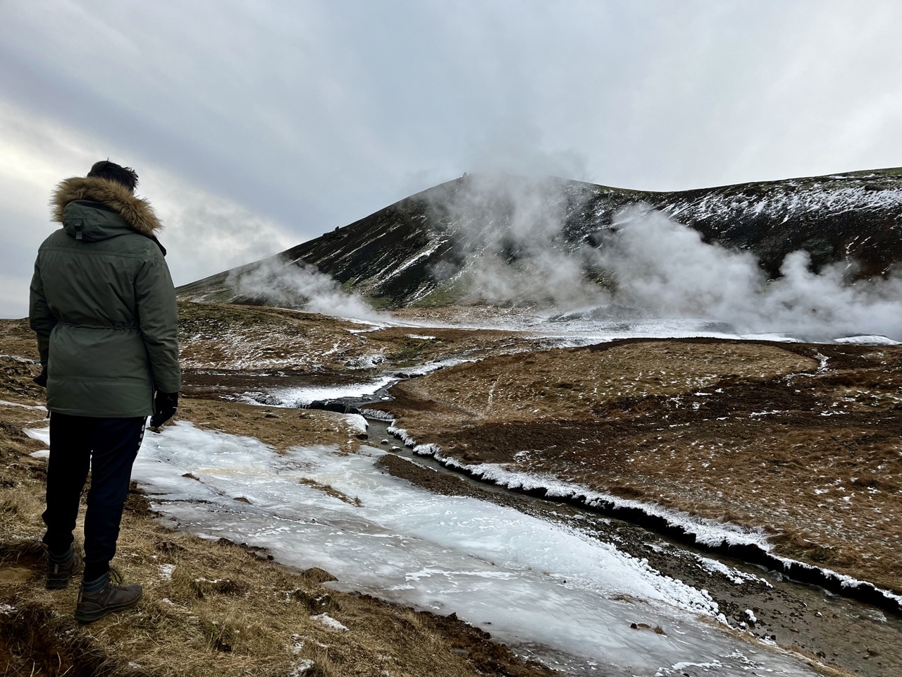 Looking up the Reykjadalur valley, steam rising ahead and the trail glazed with ice