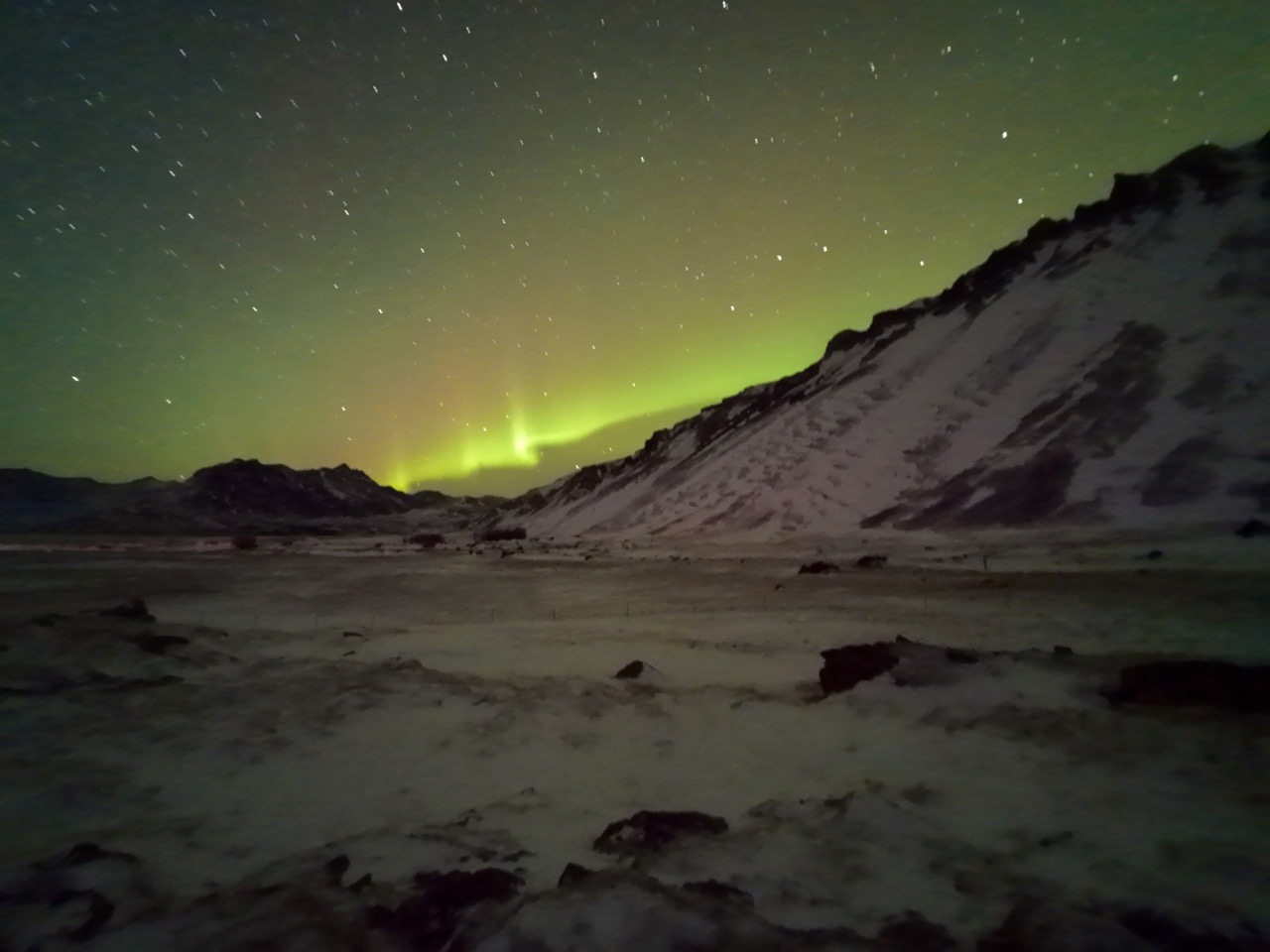 Green aurora stripes over the snowy mountains, caught by long exposure